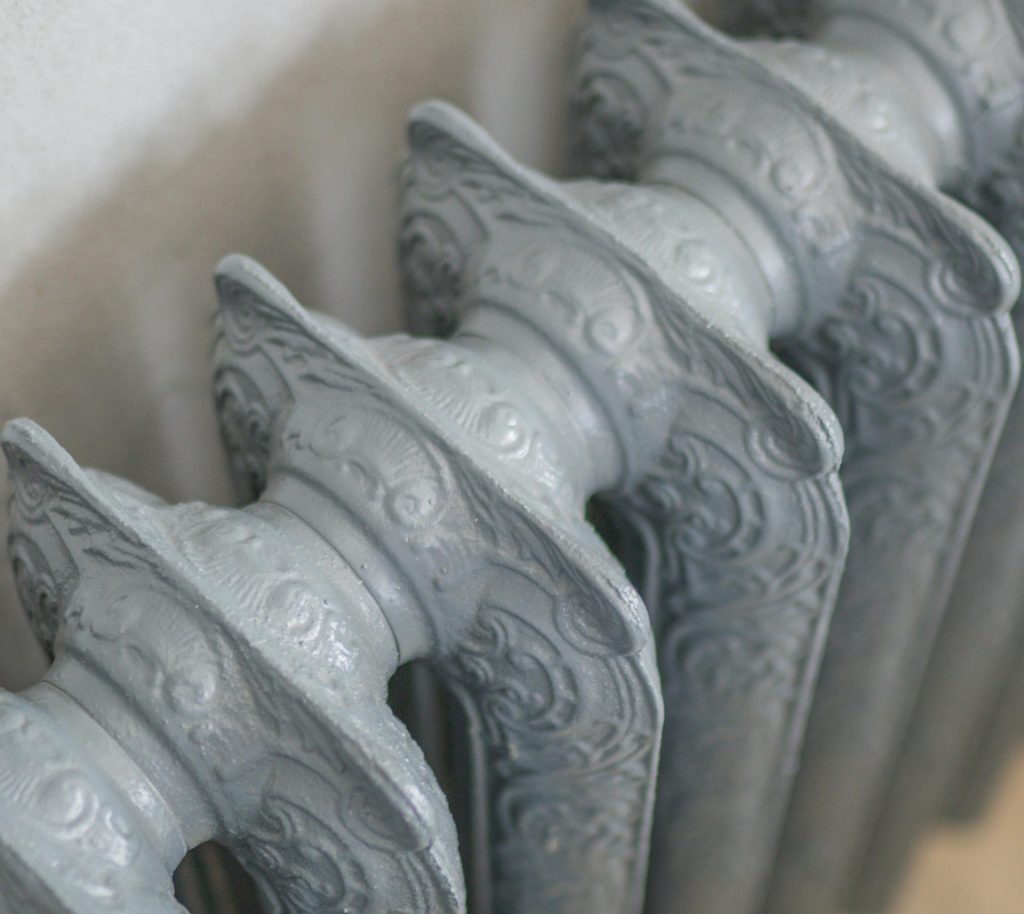 A detailed close-up of an ornate vintage cast iron radiator indoors.