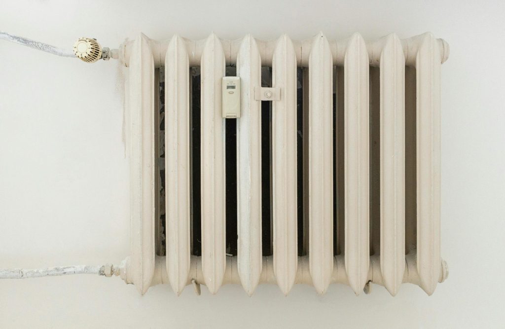 A classic white metal radiator on a plain wall, showcasing minimalist interior design.